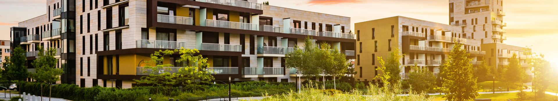 Moderne Wohngebäude bei Sonnenuntergang, die warmes Licht und Schatten auf die Fassaden werfen.