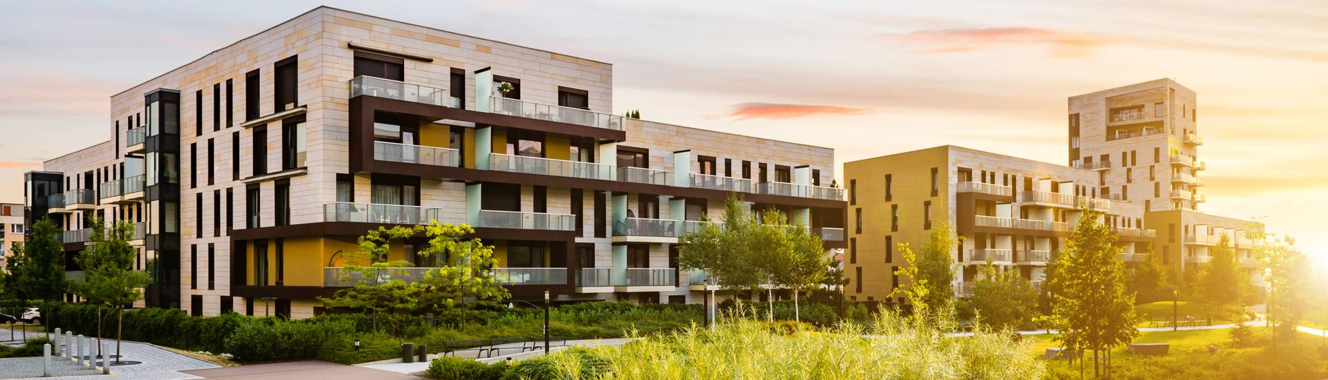Moderne Wohngebäude bei Sonnenuntergang, die warmes Licht und Schatten auf die Fassaden werfen.